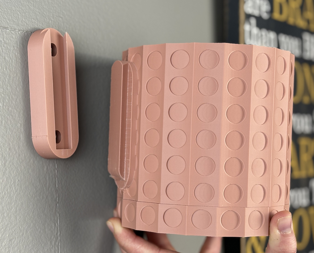 a pink wall mounted pot with removable drip tray showing how it can be removed on and off the wall, on a light grey wall
