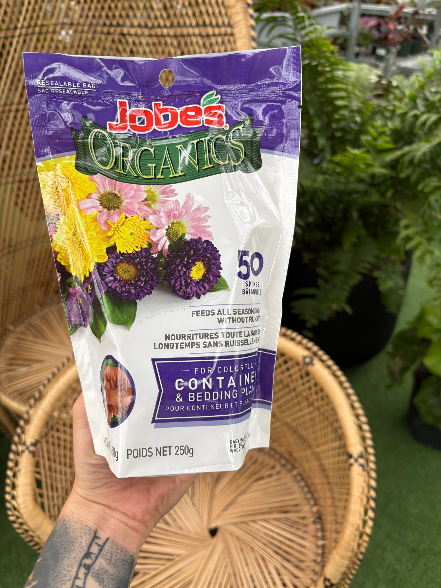 hand holding Jobe's Container and Bedding Plant Fertilizer Spikes in front of wicker chairs