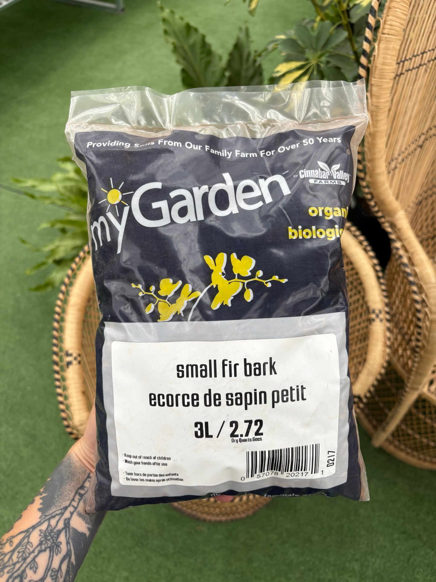 Bag of 'myGarden' organic bark on a green background with a wicker chair.