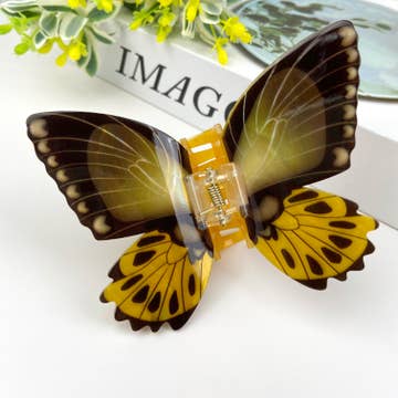 Yellow and Black Butterfly hair clip resting on white surface