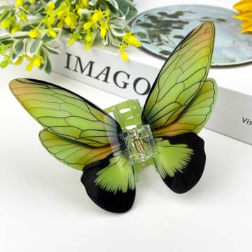 green and black butterfly hair clip resting on white surface