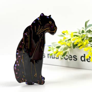 Black puma hair clip resting on white surface
