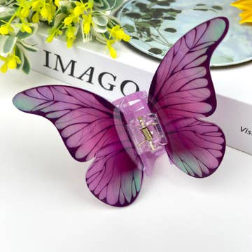 purple butterfly hair clip resting on white surface
