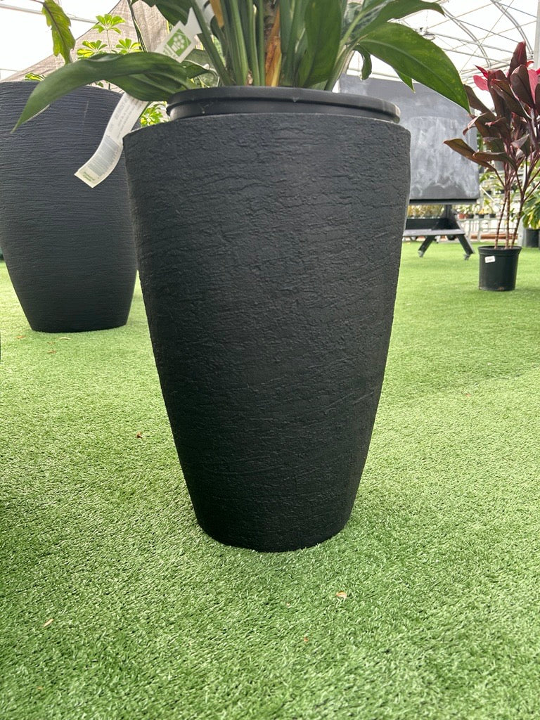 a small black planter on a grass like surface