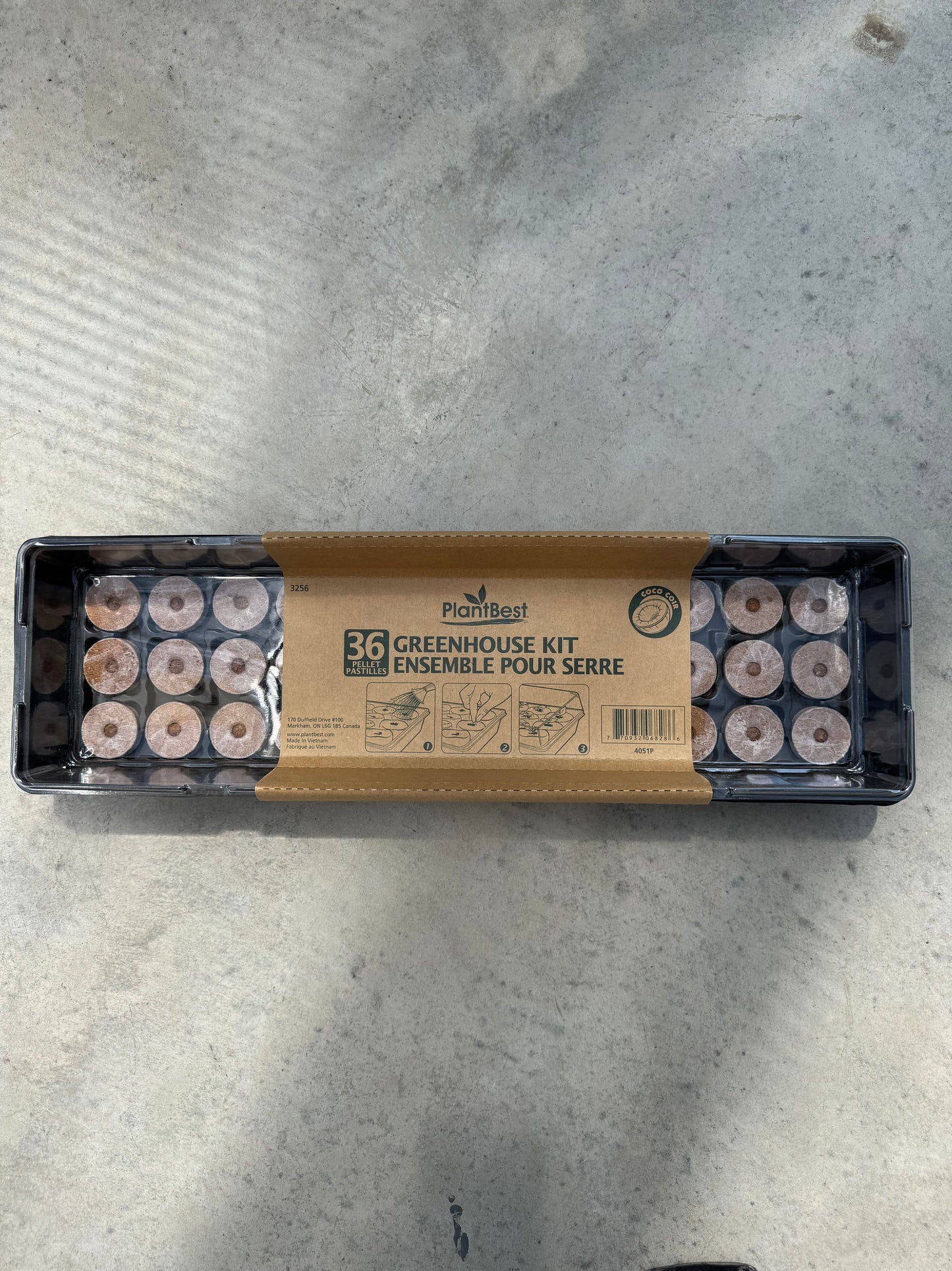 Greenhouse kit packaging with seed trays on a concrete surface