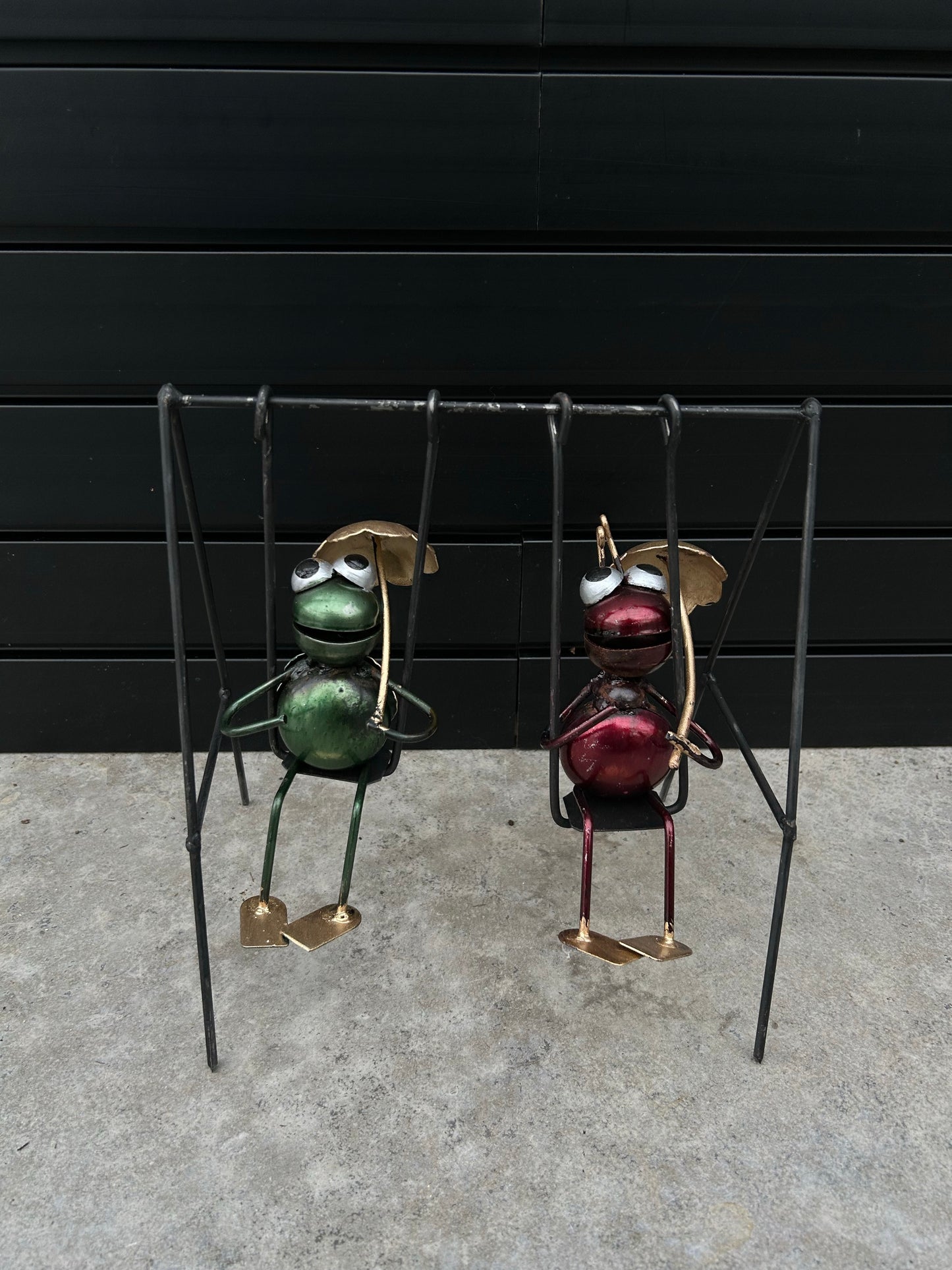 two bugs, one green one red with bigeyes istting on swings