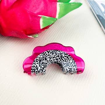 a pink white and black hair clip against a white background