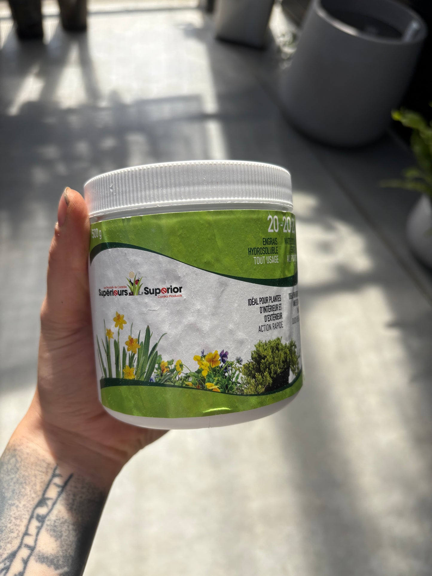 Hand holding a container with a green label on a light surface