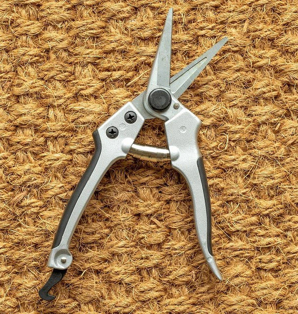 Silver pliers with black handles on a textured brown surface