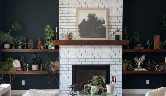 a picture of shelves styled with houseplants, thrifted decor and Kanso Designs pots with a white tile fireplace in the centre and dark green walls