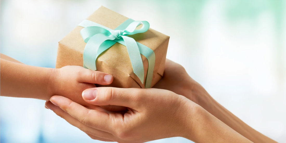 two sets of hands holding a paper wrapped gift with a teal bow
