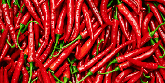 an overhead shot of many bright red thin peppers with vibrant green stems