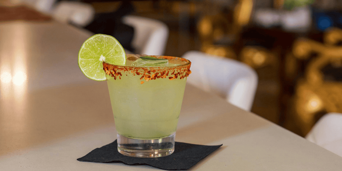a spicy margarita resting on a napkin with a lime wheel