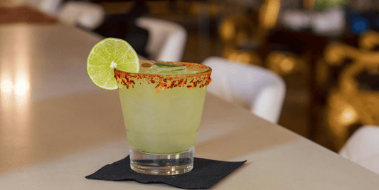 a spicy margarita resting on a napkin with a lime wheel