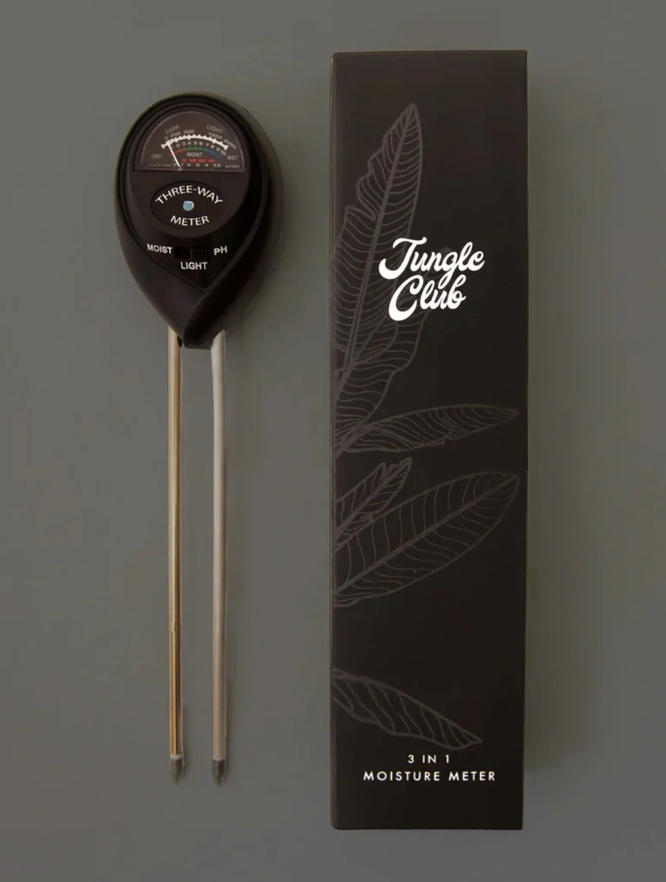 a black moisture meter resting next to its packaged jungle club box against a grey background