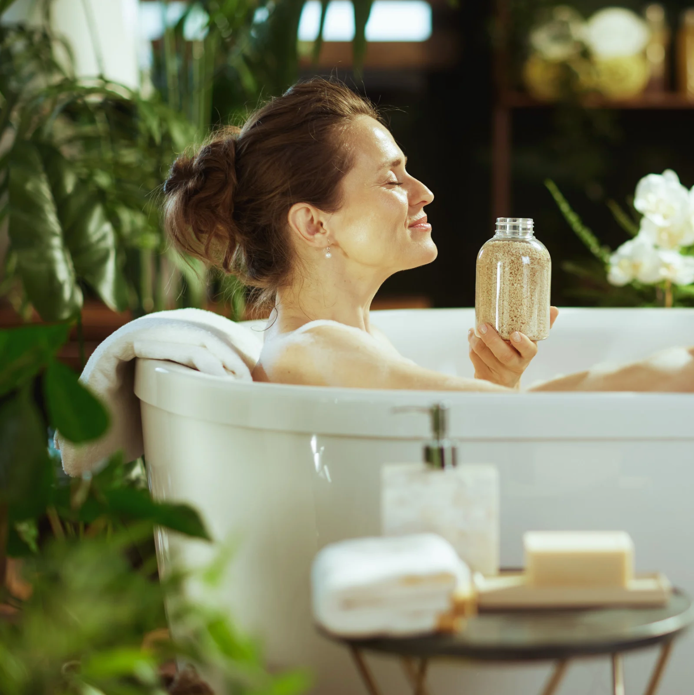 a woman resting in a bathtub surrounded by tropical houseplants