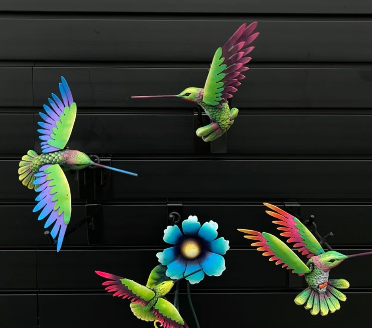 bright coloured metal outdoor decor hummingbirds against a black wall