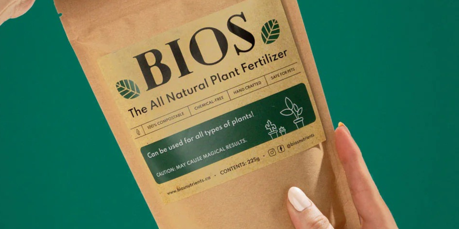 a hand holding a bag of bios houseplant fertilizer with a green background 