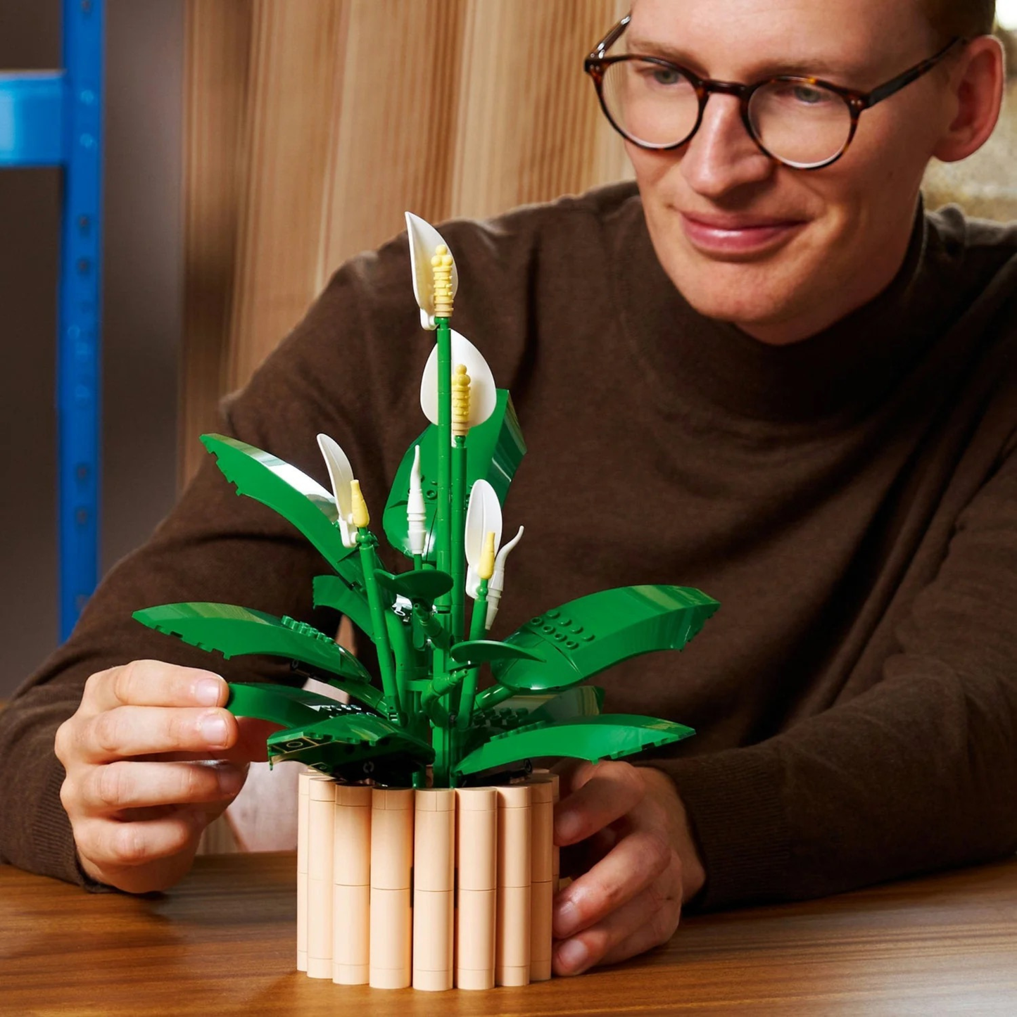 LEGO Botanicals Peace Lily 11504 building set being built by a man wearing glasses and a brown shirt