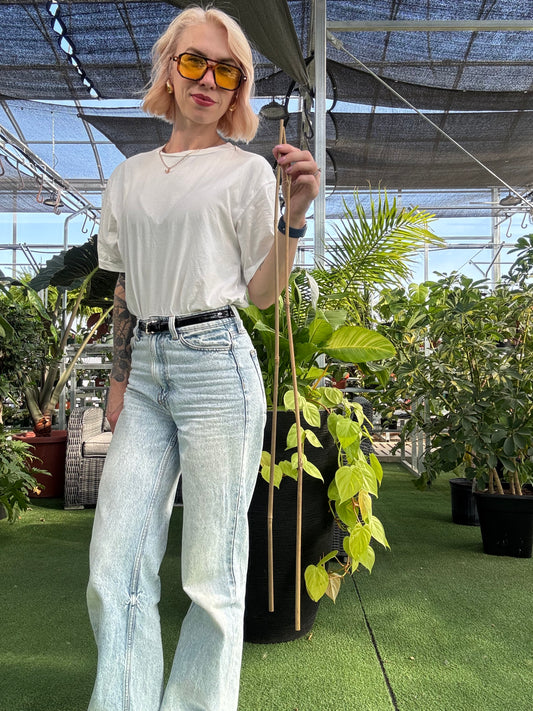 a girl wearing jeans and a white shirt holding two bamboo plant stakes 