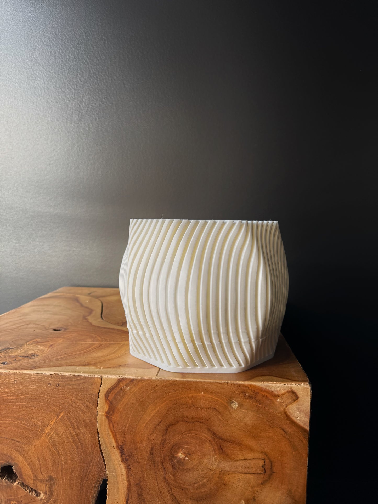 Two 3D printed pots, one white and one black, with a removable drip tray, placed on a wooden surface against a dark background.