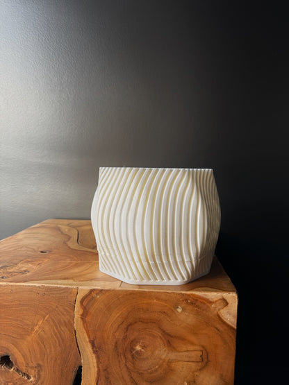 Two 3D printed pots, one white and one black, with a removable drip tray, placed on a wooden surface against a dark background.