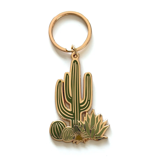a gold keychain featuring one large cactus and may smaller cacti around the bottom against a white background
