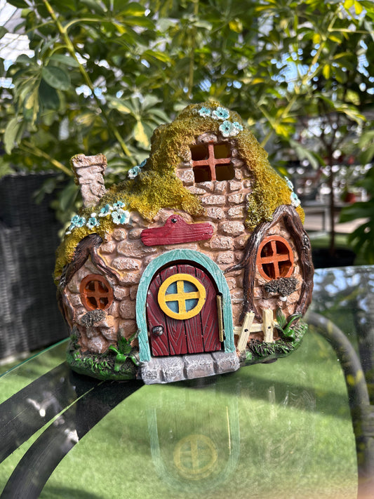 Miniature fairy house with moss and flowers on a blurred natural background