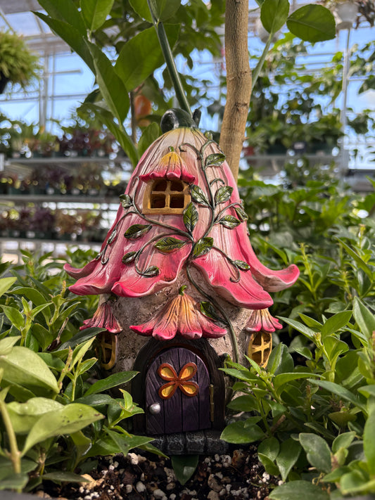 Decorative fairy house with pink flower design in a garden setting