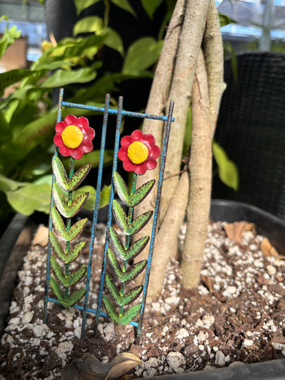 Decorative Fairy Garden Trellis with red flowers and green leaves in a pot.