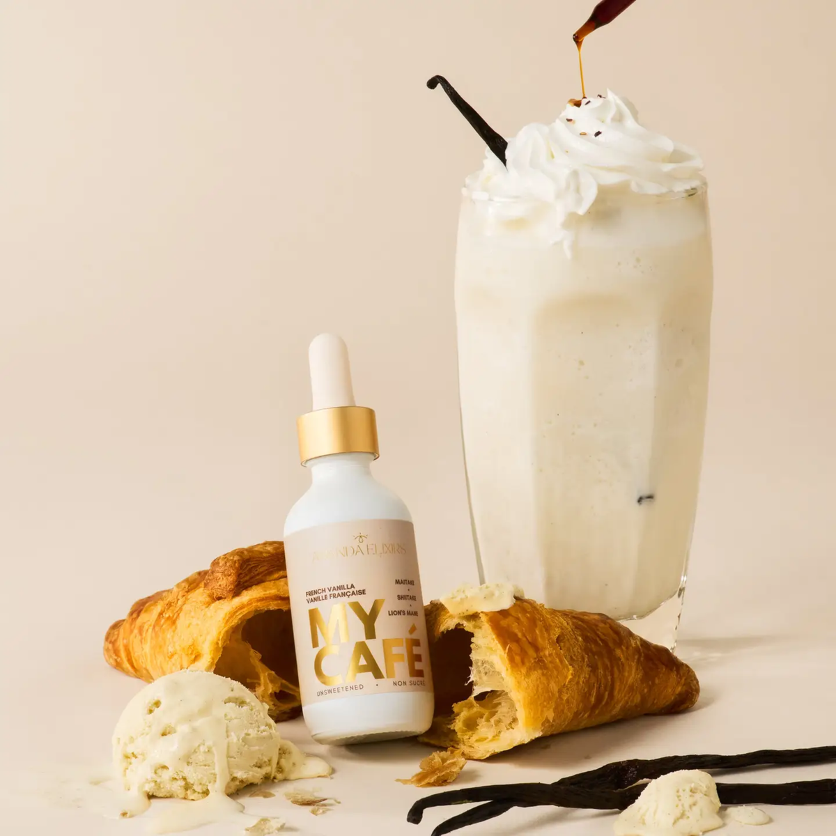 a white proper bottle with a tan label that says my cafe French vanilla with the bottle resting on a croissant with a white French vanilla iced beverage behind it and aa cream coloured white background
