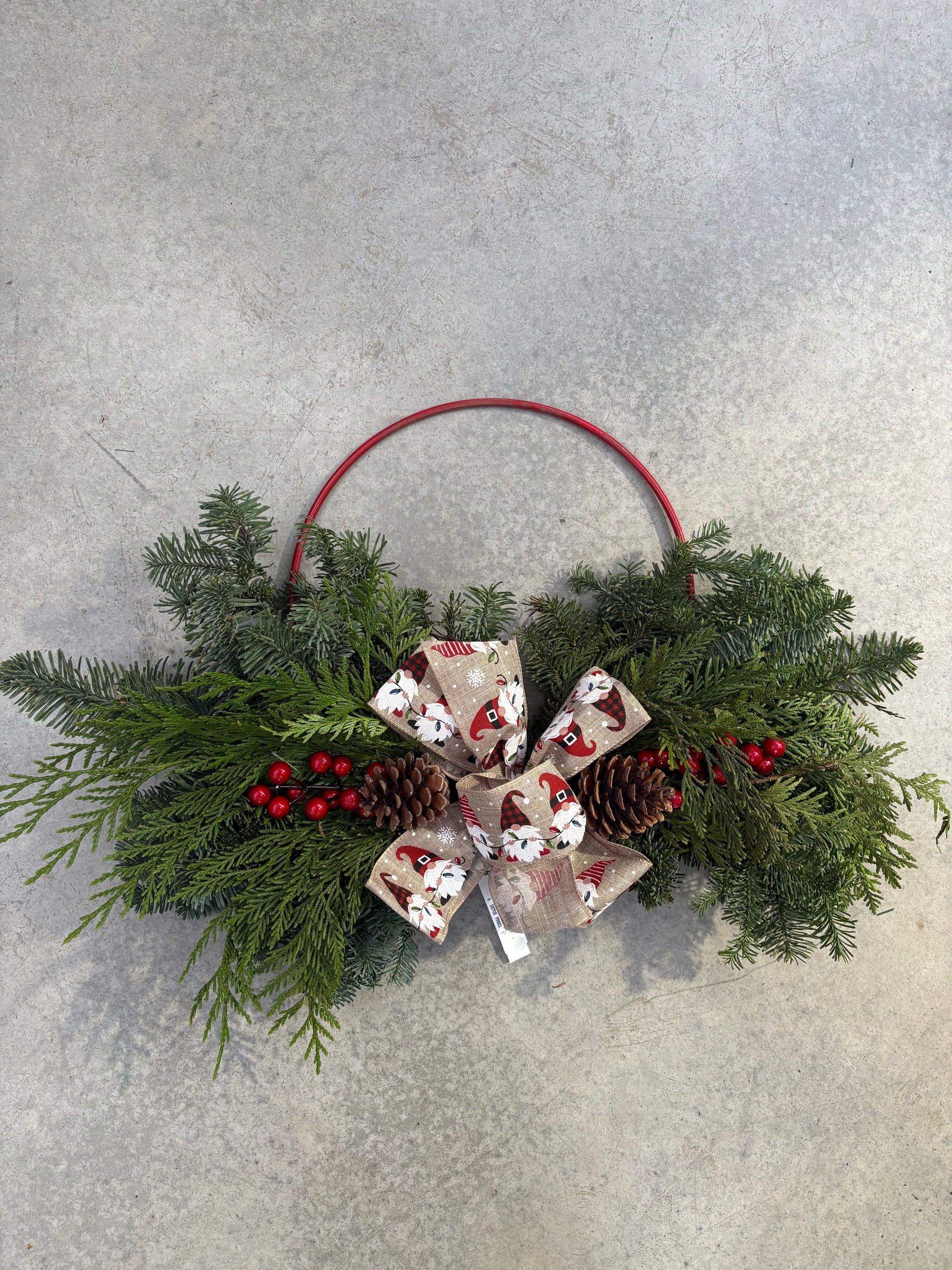 Hoop Golden Forest Wreath 24" wreath with greenery, pinecones, and red berries on a light gray background