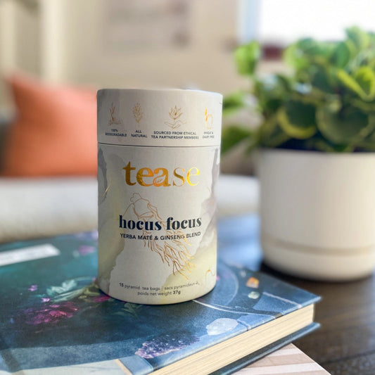 Tea canister labeled 'tease hocus focus' on a book with a blurred indoor background