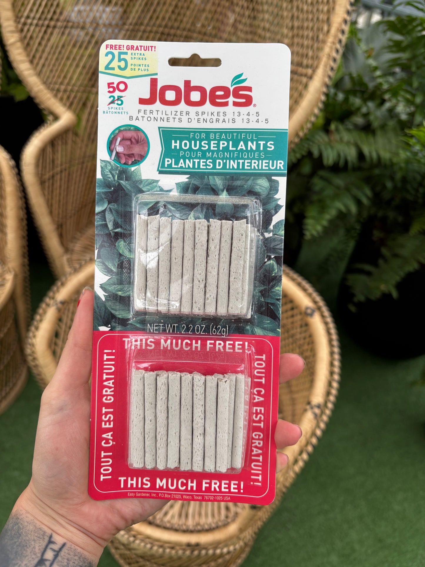 hand holding package of Houseplant Fertilizer Spikes in front of wicker chairs 