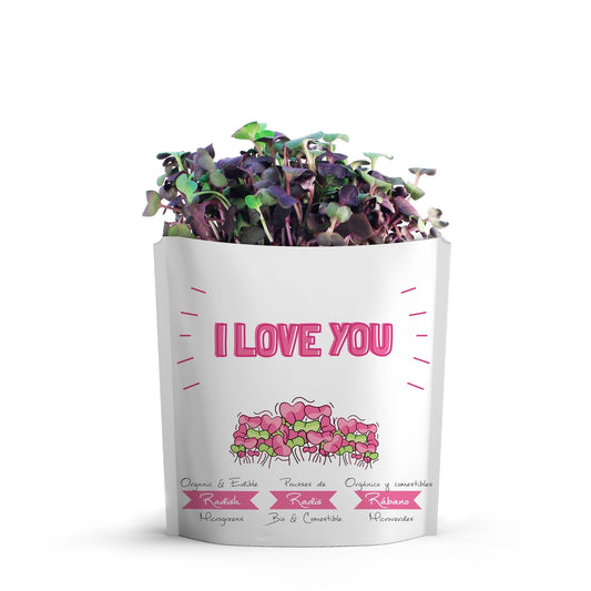 A white package printed with 'I LOVE YOU' in pink, along with small radish micro green illustrations with green and purple radish microgreensgrowing from the top of the package, on a white background.