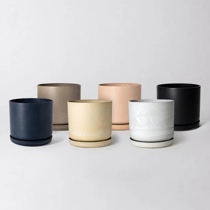 Set of six recycled material planters in various colors on a light gray background