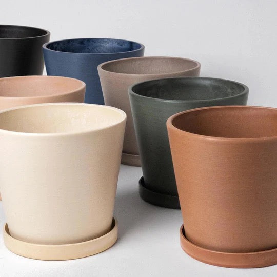 Set of various colored recycled material pots on a light gray background