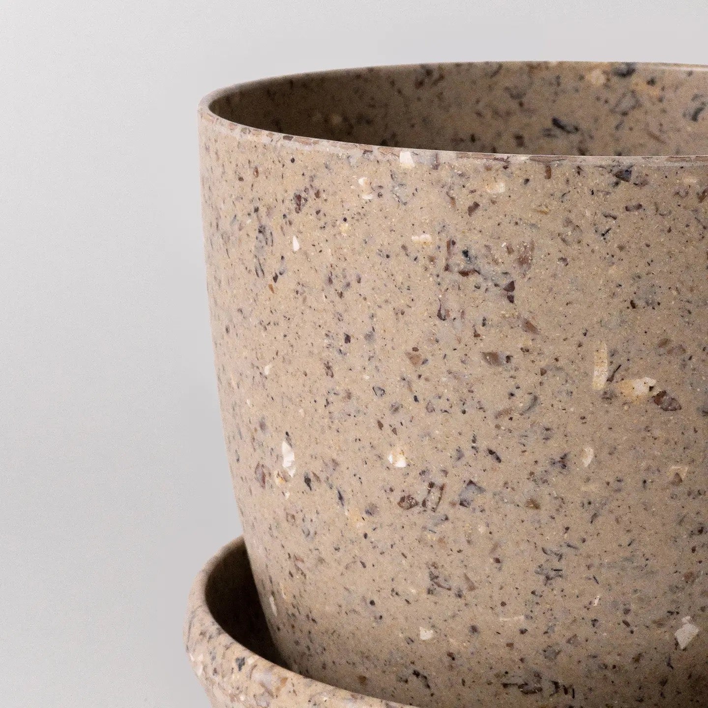 Close-up of a recycled material pot with a speckled texture on a light gray background