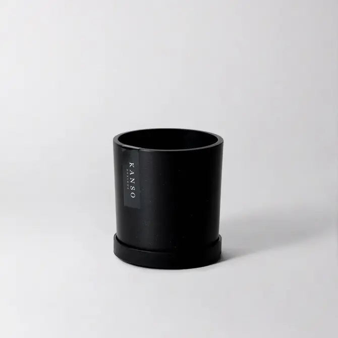 Black pot with Kanso Designs branding on a light gray background