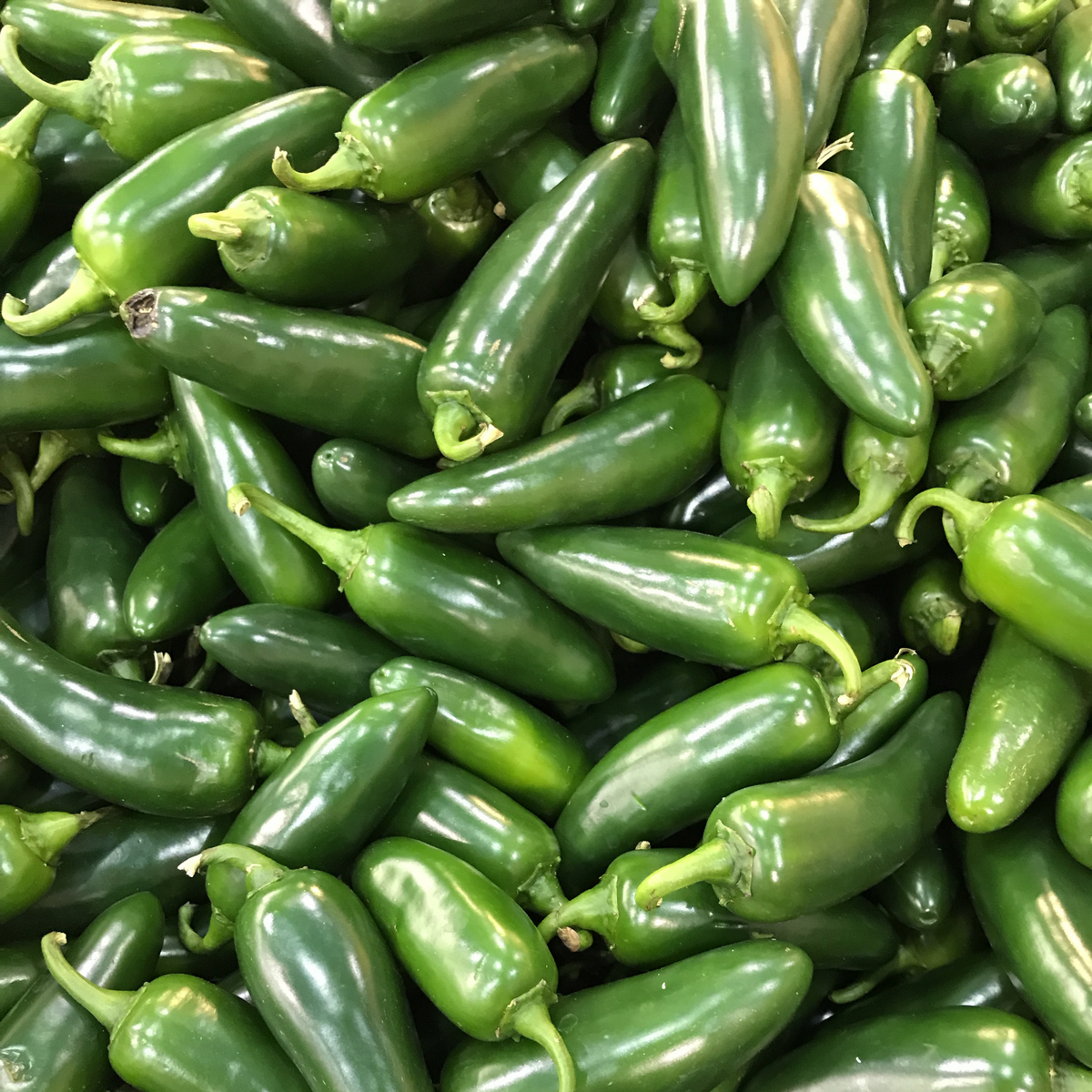 a large pile of bright green la bombs jalapeño peppers with green stems