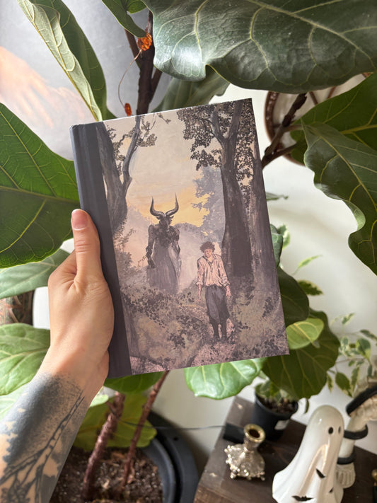 Person holding a Laura Alexander - Fantasy Art - Journal amidst green leaves