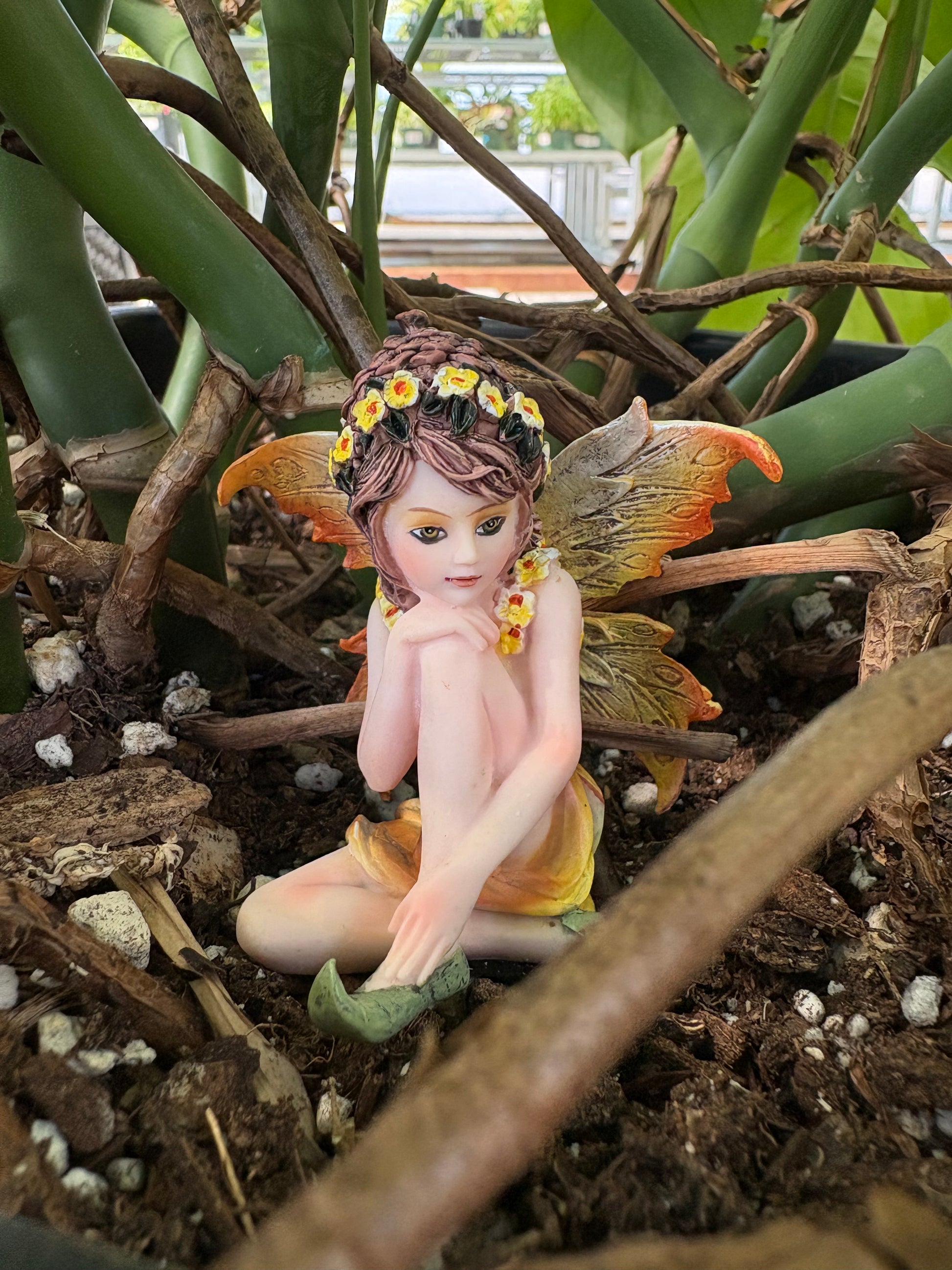 Fairy figurine among plants with a blurred background