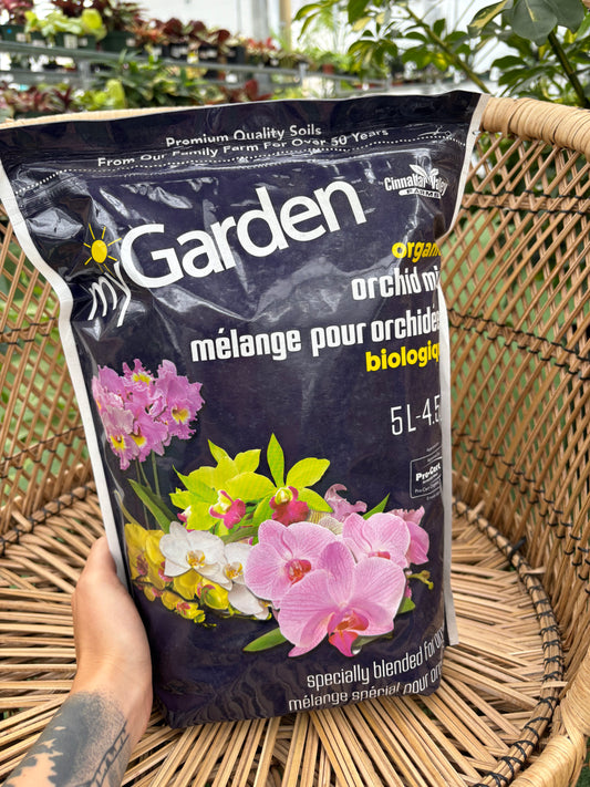 Bag of Garden orchid soil held by a person with plants in the background