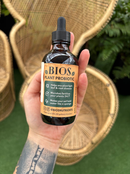 Hand holding a bottle of BIOS Plant Probiotic with a blurred natural background