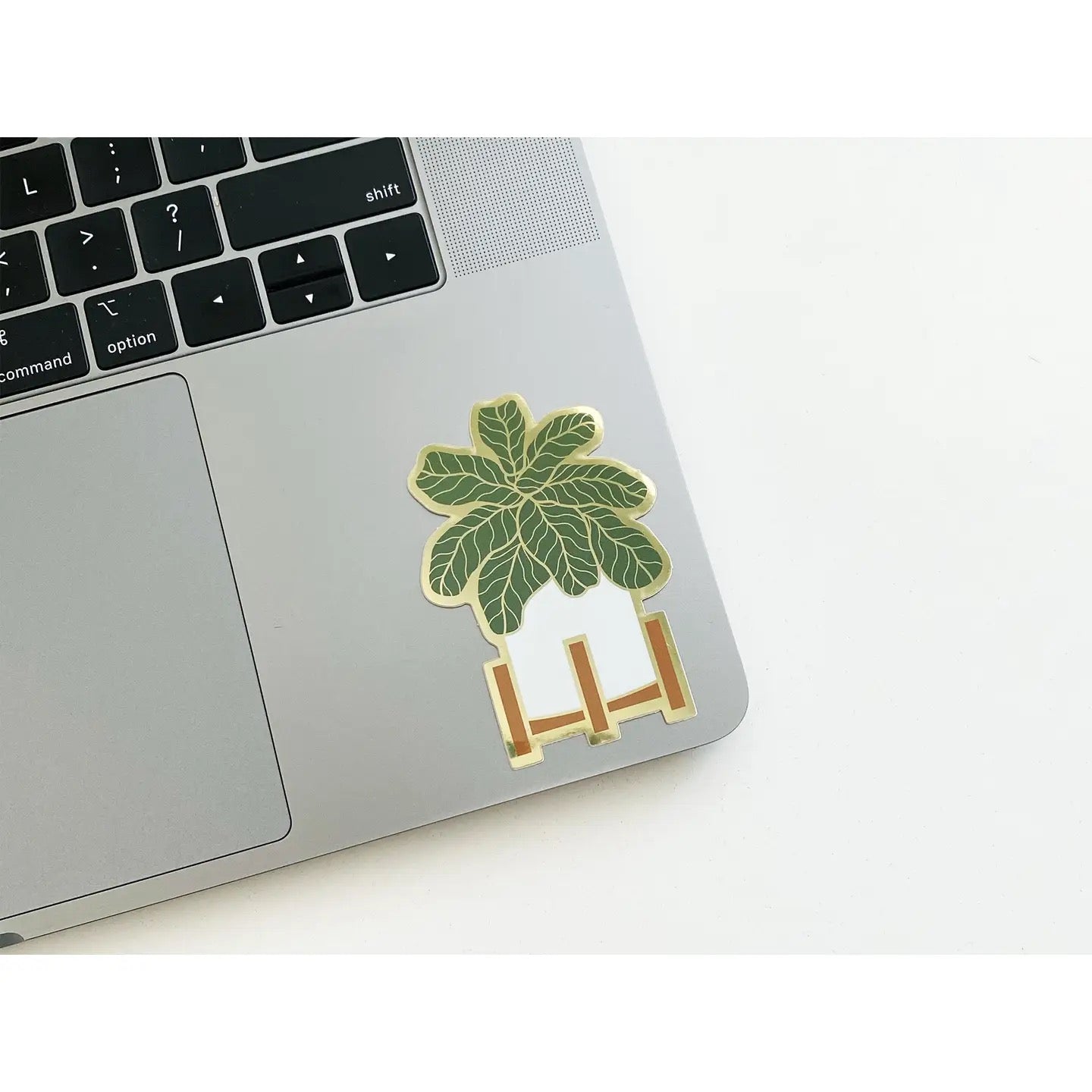 Laptop with a decorative sticker featuring a potted leafy plant on a white background