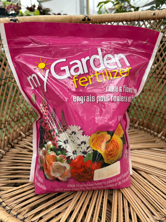 Pink bag of garden fertilizer with floral designs on a wicker surface