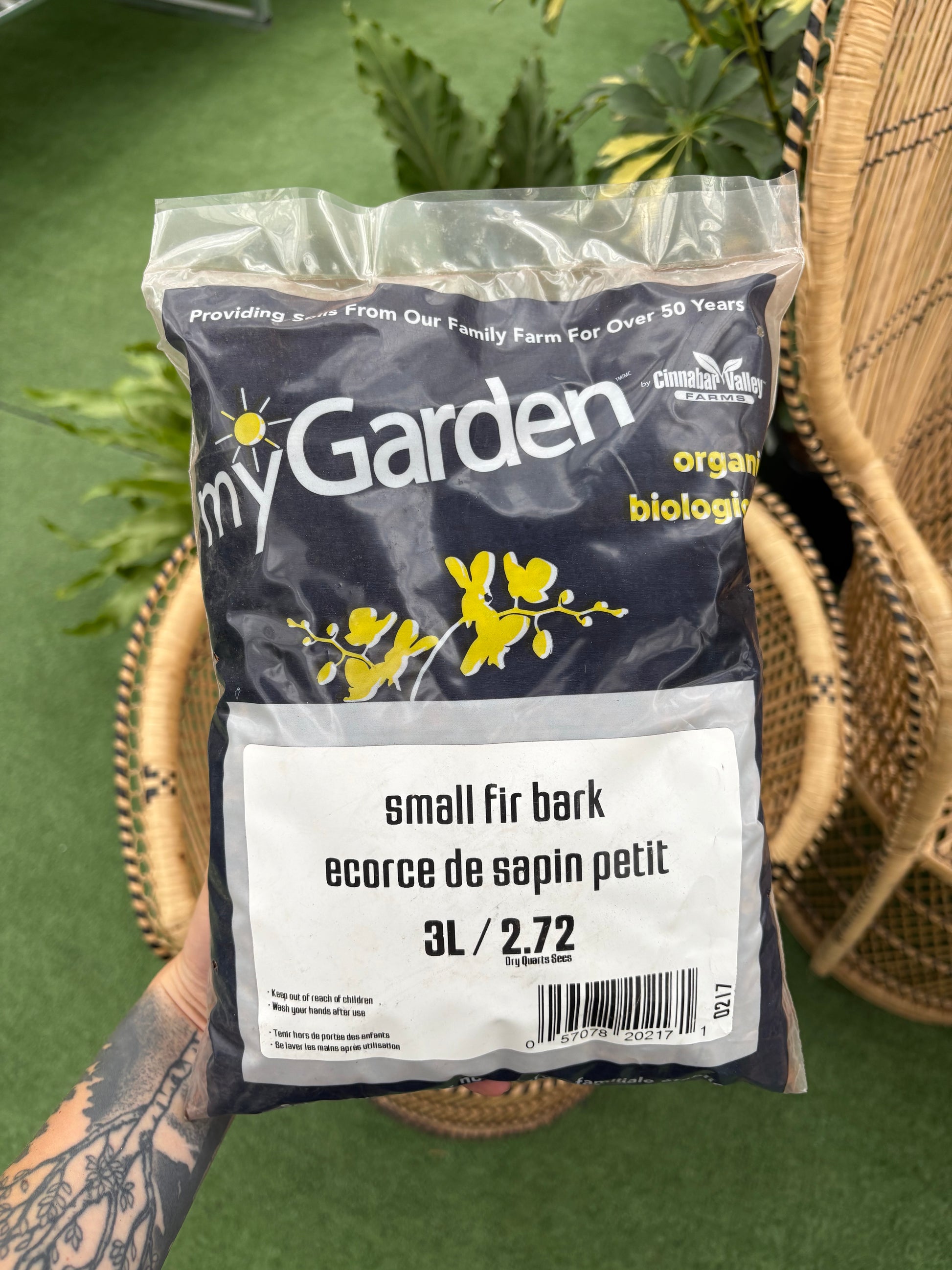 Bag of 'myGarden' organic bark on a green background with a wicker chair.