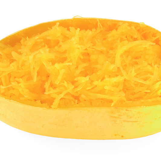 A close-up of shredded yellow-orange spaghetti squash piled in the shallow yellow-orange just of the vegetable on a white background.