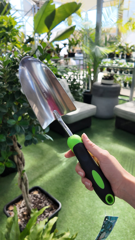 Person holding a Steel Trowel gardening tool with a blurred garden background