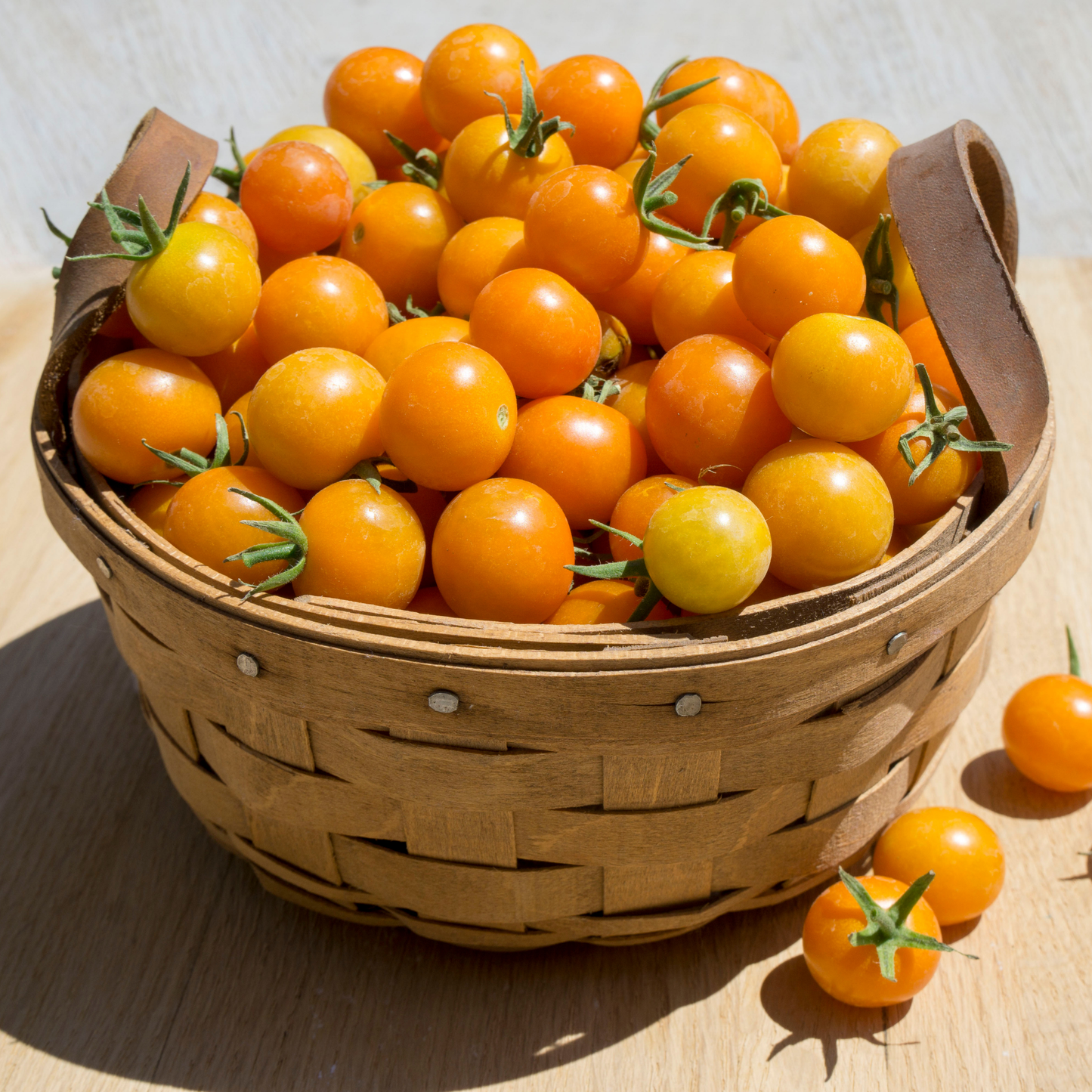 a wicker basket of small golden sun gold cherry tomatoes on a wooden surface